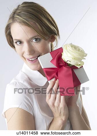 Stock Photo - Woman with a gift and white rose blossom. Fotosearch