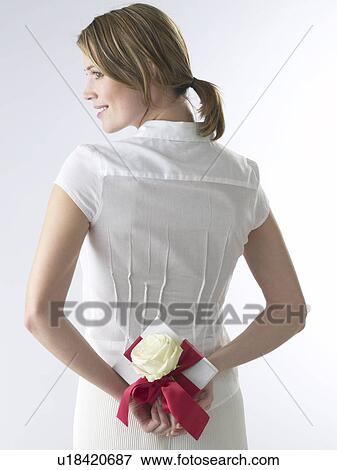 Stock Photo - Woman with a gift and white rose blossom. Fotosearch