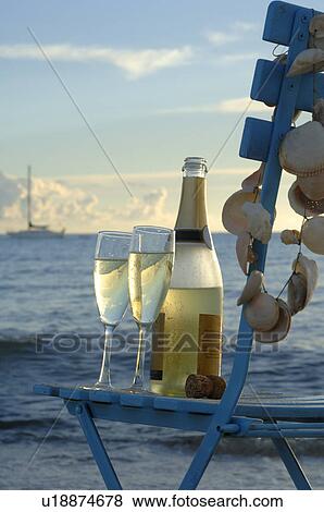Stock Photo - A bottle of sparkling wine on a chair at the beach. Fotosearch