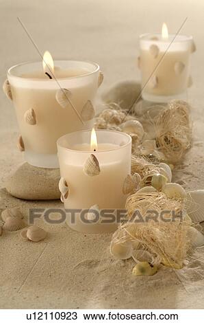 Stock Image - Candles decorated with mussels in the sand. Fotosearch
