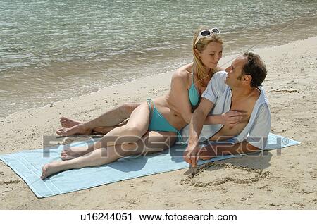 Stock Image - Couple on the beach on a mat. Fotosearch
