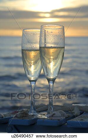 Stock Photo - Two glasses of sparkling wine in the sunset at the sea. Fotosearch