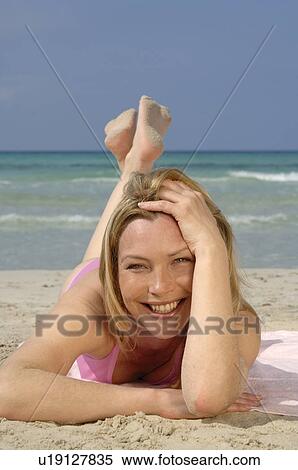 Woman is lying on the beach View Large Photo Image Stock Photography - Woman is lying on the beach. Fotosearch