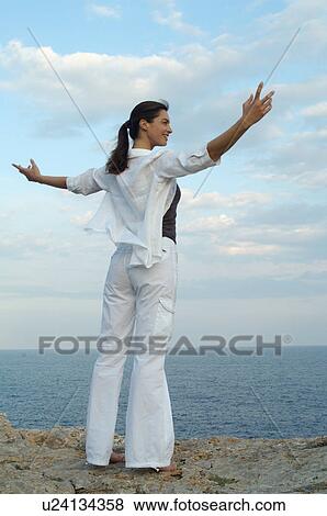 Stock Photo - Woman on a rock at the sea. Fotosearch