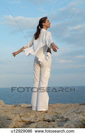 Stock Photograph - Woman on a rock at the sea. Fotosearch