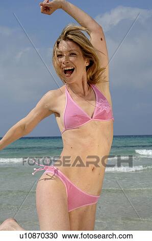 Stock Image - Woman on the beach is reaching out in the air. Fotosearch