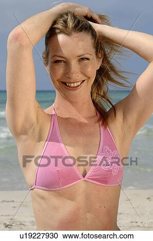 Woman on the beach puts her hands on her hair View Large Photo Image Stock Image - Woman on the beach puts her hands on her hair. Fotosearch
