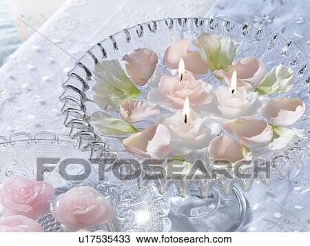 Stock Image - Arrangement of blossoms and swimming candles in a glass bowl. Fotosearch