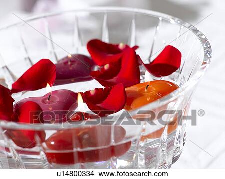 Picture - Arrangement of red rose petals and swimming candles in a glass bowl. Fotosearch