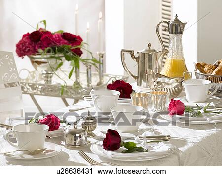 Stock Image - Breakfast table decorated with red roses. Fotosearch