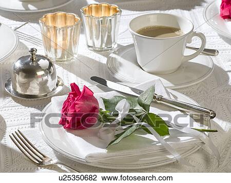 Stock Image - Coffee table place setting decorated with a red rose. Fotosearch