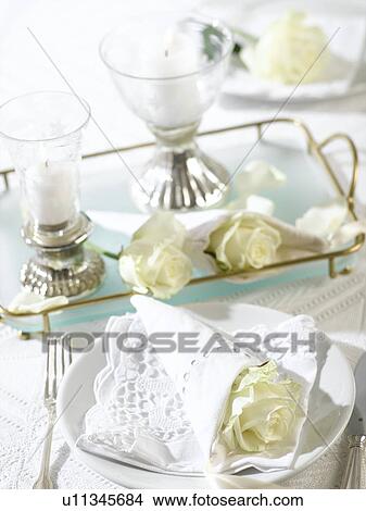 Picture - Place setting with a white rose wrapped in a napkin. Fotosearch