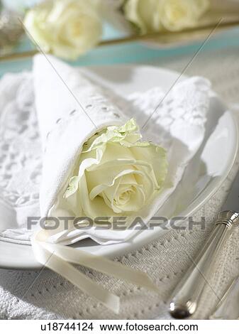Picture - Place setting with a white rose wrapped in a napkin. Fotosearch