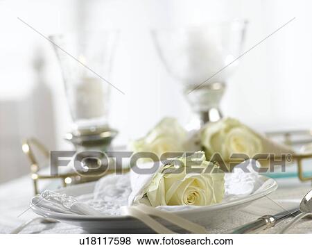 Two table lanterns and a place setting with a white rose wrapped in a napkin View Large Photo Image Stock Photo - Two table lanterns and a place setting with a white rose wrapped in a napkin. Fotosearch