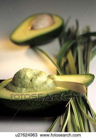 Stock Image - Avocado half with body mask (Persea americana). Fotosearch