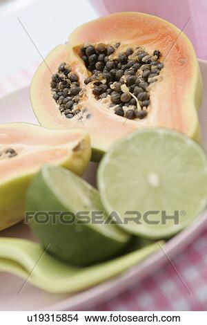 Picture - Sliced pawpaw tree fruit and limes. Fotosearch
