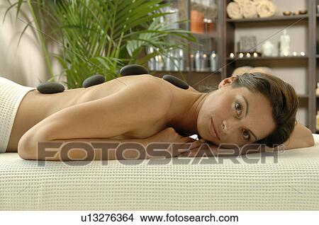 Picture - woman resting on her stomach with pebbles on her back. Fotosearch