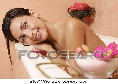 Stock Image - Woman in bath tub with petals. Fotosearch