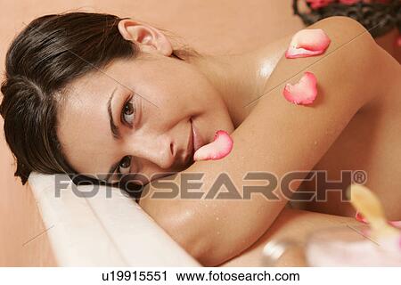 Stock Image - Woman in bath tub with petals. Fotosearch