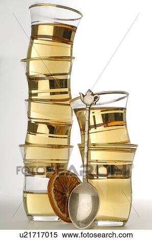 Stock Photography - A batch of tea glasses with tea spoons and a slice of orange. Fotosearch
