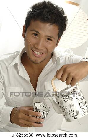 Asian man is pouring tea into a teacup View Large Photo Image Stock Image - Asian man is pouring tea into a teacup. Fotosearch