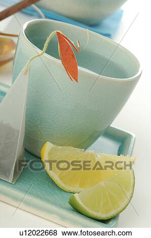 Stock Photo - Tea mug with a tea bag and lemons and limes. Fotosearch