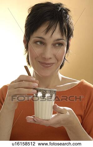 Stock Image - Woman immerses cinnamon stick in Chai tea. Fotosearch