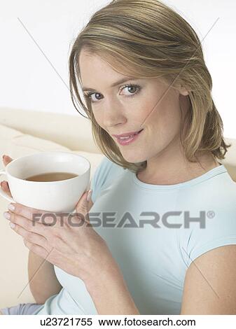 Stock Photography - Woman on the sofa drinking a cup of tea. Fotosearch