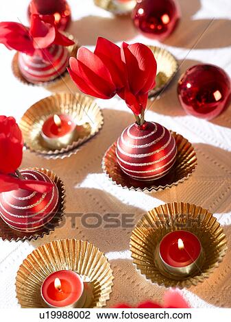 Stock Image - Christmas table decoration with red candles, cyclamen and Christmas tree balls. Fotosearch