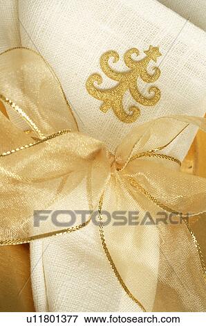 Stock Photo - Napkin with a Christmas tree pattern tied with a golden ribbon. Fotosearch