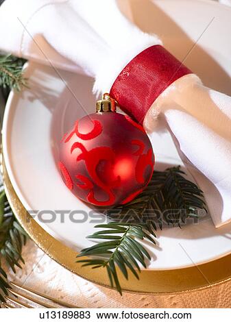 Stock Image - Place cover with a white napkin, a red Christmas tree ball and a fir branch. Fotosearch