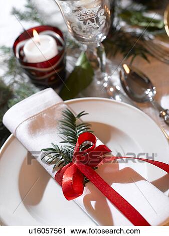 Stock Image - White napkin decorated with a fir branch and a red ribbon. Fotosearch