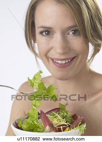 Stock Image - Woman is eating salad. Fotosearch