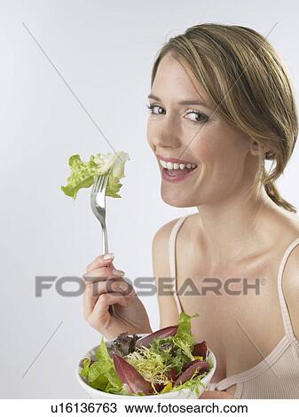 Stock Image - Woman is eating salad. Fotosearch