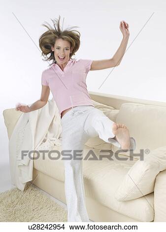 Woman is jumping onto the sofa View Large Photo Image Picture - Woman is jumping onto the sofa. Fotosearch
