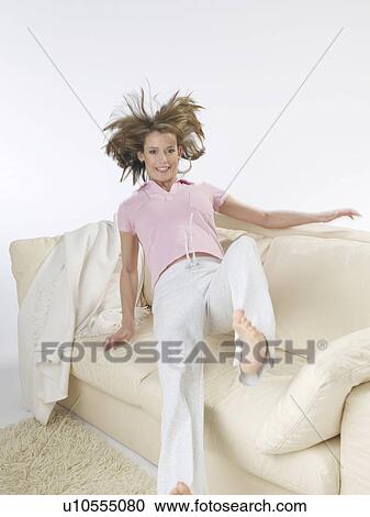 Stock Image - Woman is jumping onto the sofa. Fotosearch