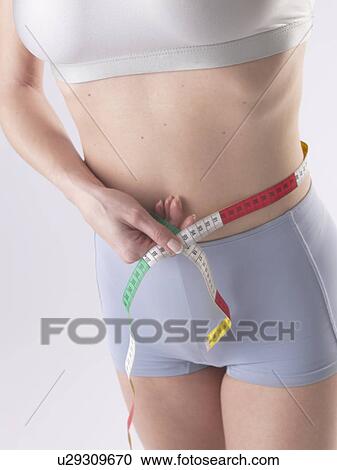 Woman is measuring her waist View Large Photo Image Stock Image - Woman is measuring her waist. Fotosearch
