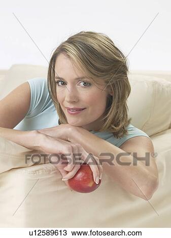 Woman on the sofa with an apple View Large Photo Image Stock Image - Woman on the sofa with an apple. Fotosearch