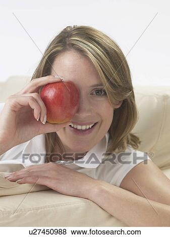 Stock Photo - Woman on the sofa with an apple. Fotosearch
