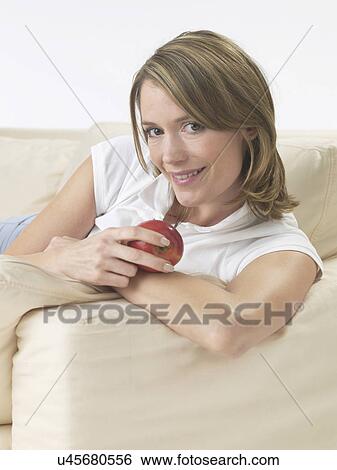 Woman on the sofa with an apple View Large Photo Image Stock Photograph - Woman on the sofa with an apple. Fotosearch