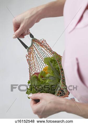 Stock Photo - Woman with fruit and vegetables in a string bag. Fotosearch