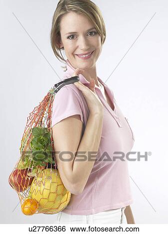 Woman with fruit and vegetables in a string bag View Large Photo Image Stock Photograph - Woman with fruit and vegetables in a string bag. Fotosearch