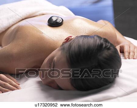 Stock Image - Hot stone massage / woman on a massage table. Fotosearch