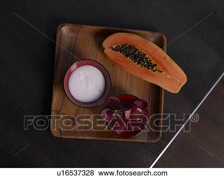 Stock Photo - Plate with a papaya, creme and a blossom. Fotosearch