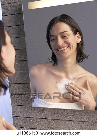 Stock Image - Woman is creaming her decolleté. Fotosearch