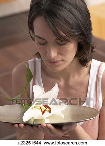 Picture - Woman is holding a bowl with lily blossom. Fotosearch
