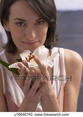 Stock Image - Woman is holding a lily blossom. Fotosearch