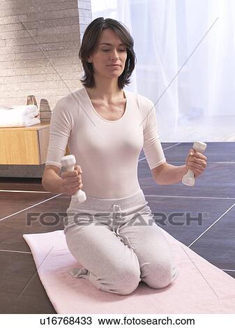 Stock Image - Woman training with barbells. Fotosearch