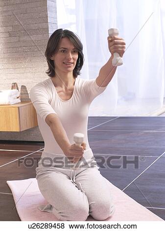 Stock Photo - Woman training with barbells. Fotosearch