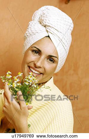 Stock Photo - Woman in the bathroom with a bunch of camomile. Fotosearch